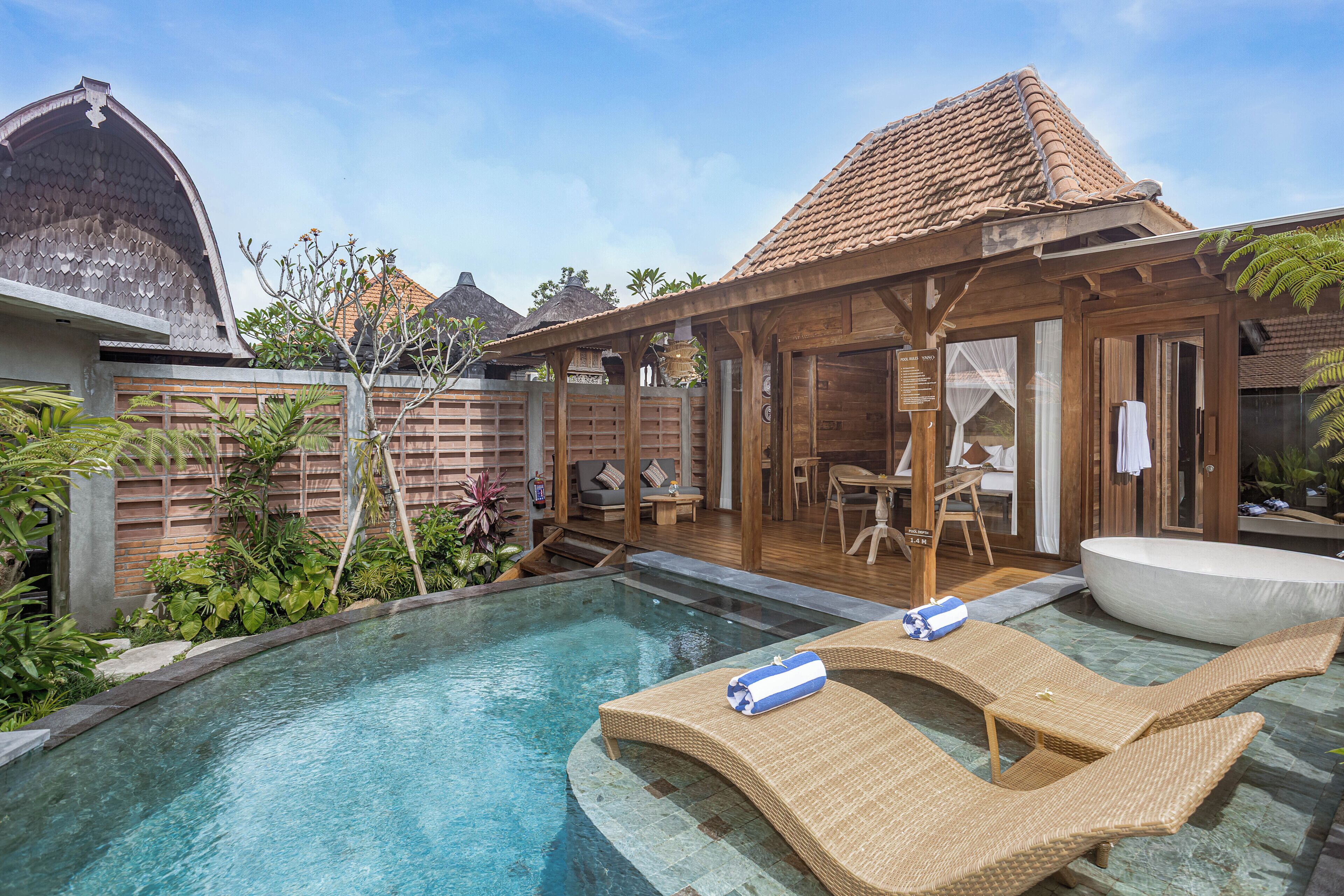 A pool with lounge chairs, a wooden deck, and a covered seating area.