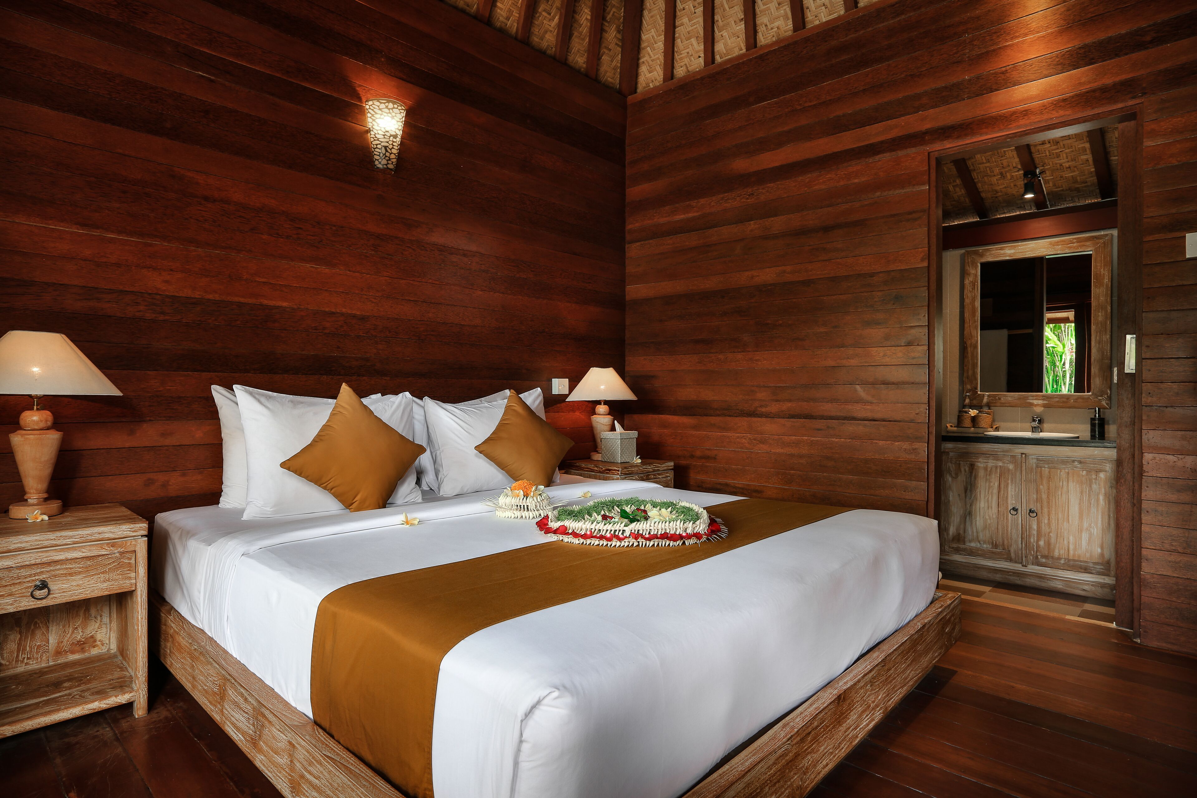 A wooden-paneled bedroom with a large bed, two bedside tables with lamps, and a wooden wardrobe.