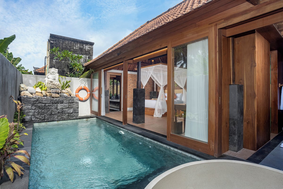 A swimming pool with a stone wall and a wooden deck.