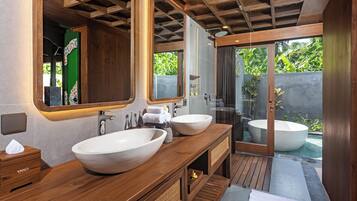 A bathroom with two large sinks, a bathtub, wooden vanity, and a glass shower enclosure.