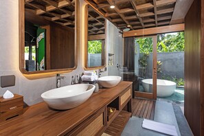 A bathroom with two large sinks, a bathtub, wooden vanity, and a glass shower enclosure. - Yana Villas Kemenuh by GenuineHost (Sukawati)