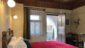 Una camera da letto con una coperta rossa, una testiera in legno e una finestra con tende leggere.