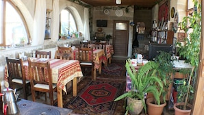 Un'accogliente sala da pranzo con tavoli e sedie in legno, un angolo caffè e piante in vaso.
