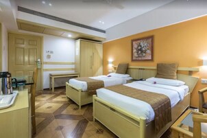 Ένα δωμάτιο ξενοδοχείου με δύο κρεβάτια, ένα γραφείο, μια καρέκλα και ένα μικρό τραπέζι.