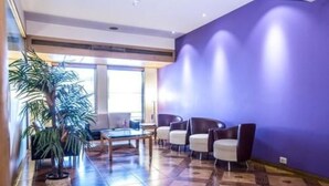 A lobby with a tiled floor, a potted plant, and seating area with chairs and a table. - The Royal Orchid (Mumbai)