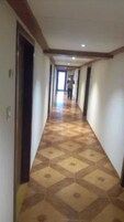 A long, narrow hallway with patterned tile flooring and wooden trim.