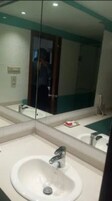 A bathroom with a large mirror, a sink, and a toilet.