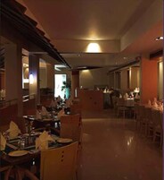 Un comedor amplio con varias mesas y sillas, una isla central y vistas al área de la cocina.