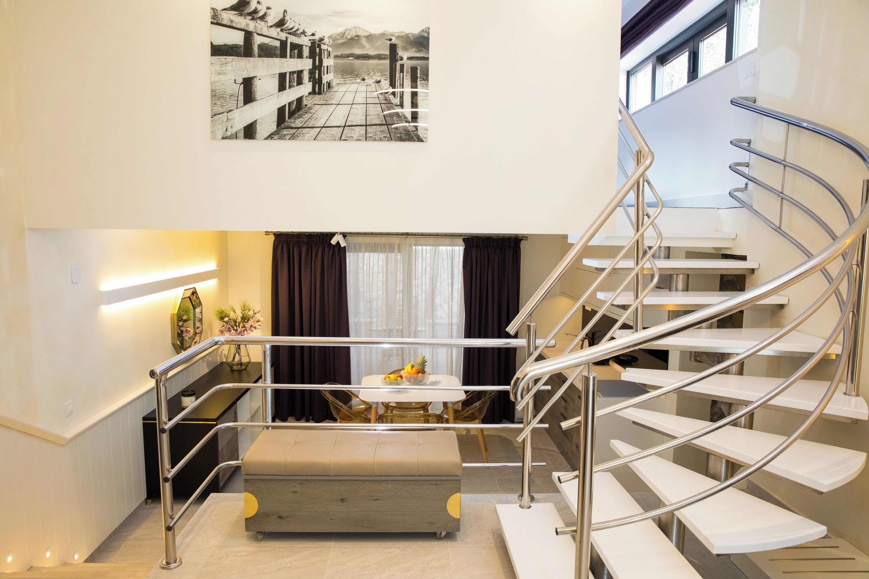 A modern interior with a spiral staircase, a dining area with a table and chairs, and a wall-mounted picture.