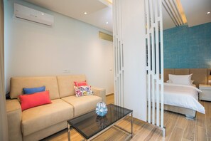 A modern hotel room with a sofa, a glass coffee table, and a bed. - Villa Diamond (Zupa dubrovacka)