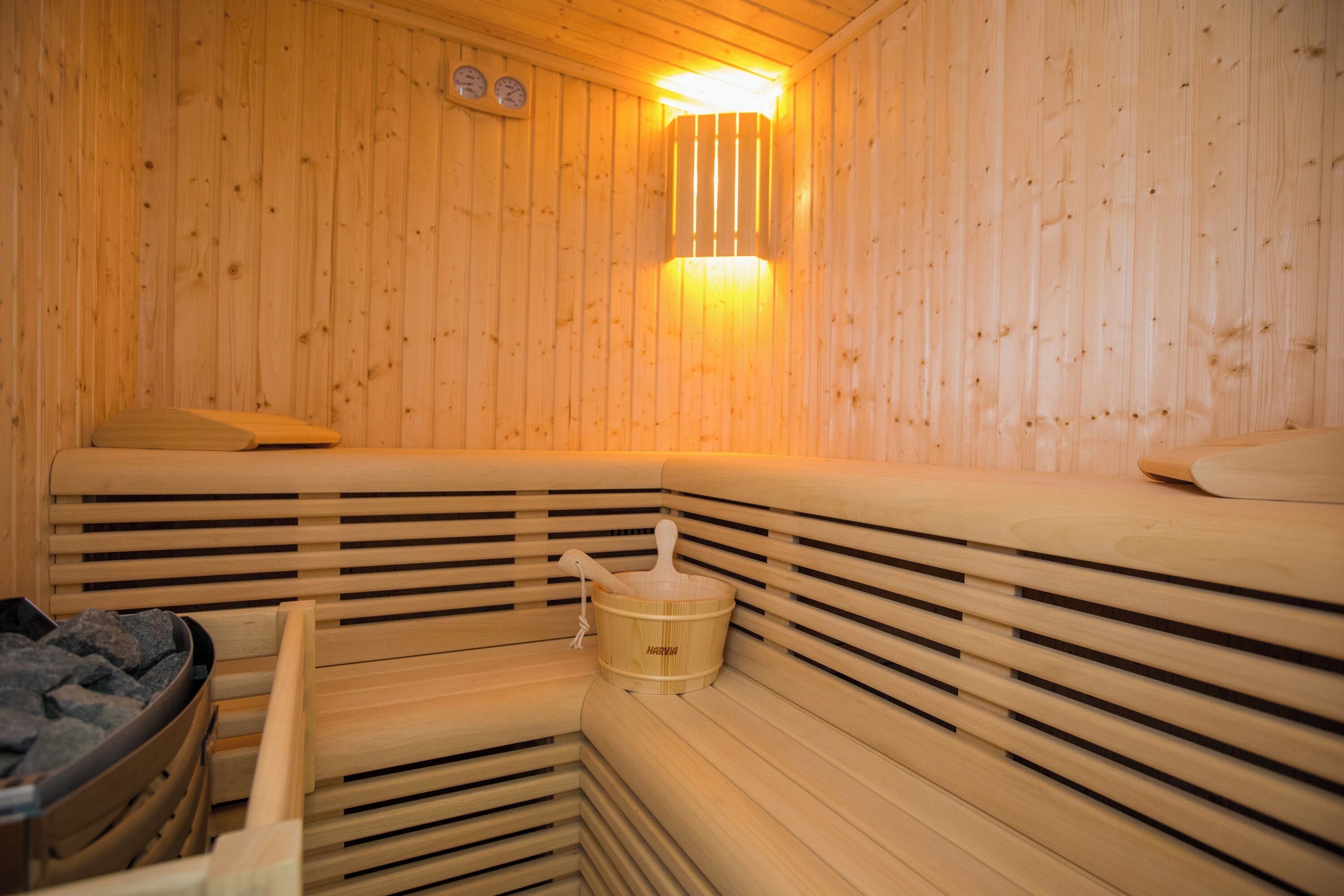 Un sauna en bois avec des bancs et un bassin en pierre.