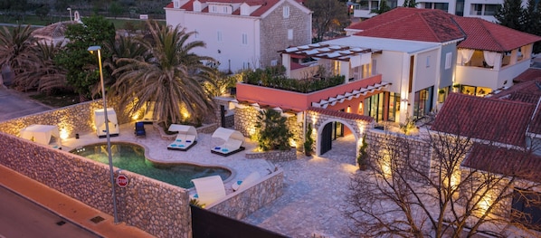 A luxurious outdoor pool area with lounge chairs and a stone wall. - Villa Diamond (Zupa dubrovacka)