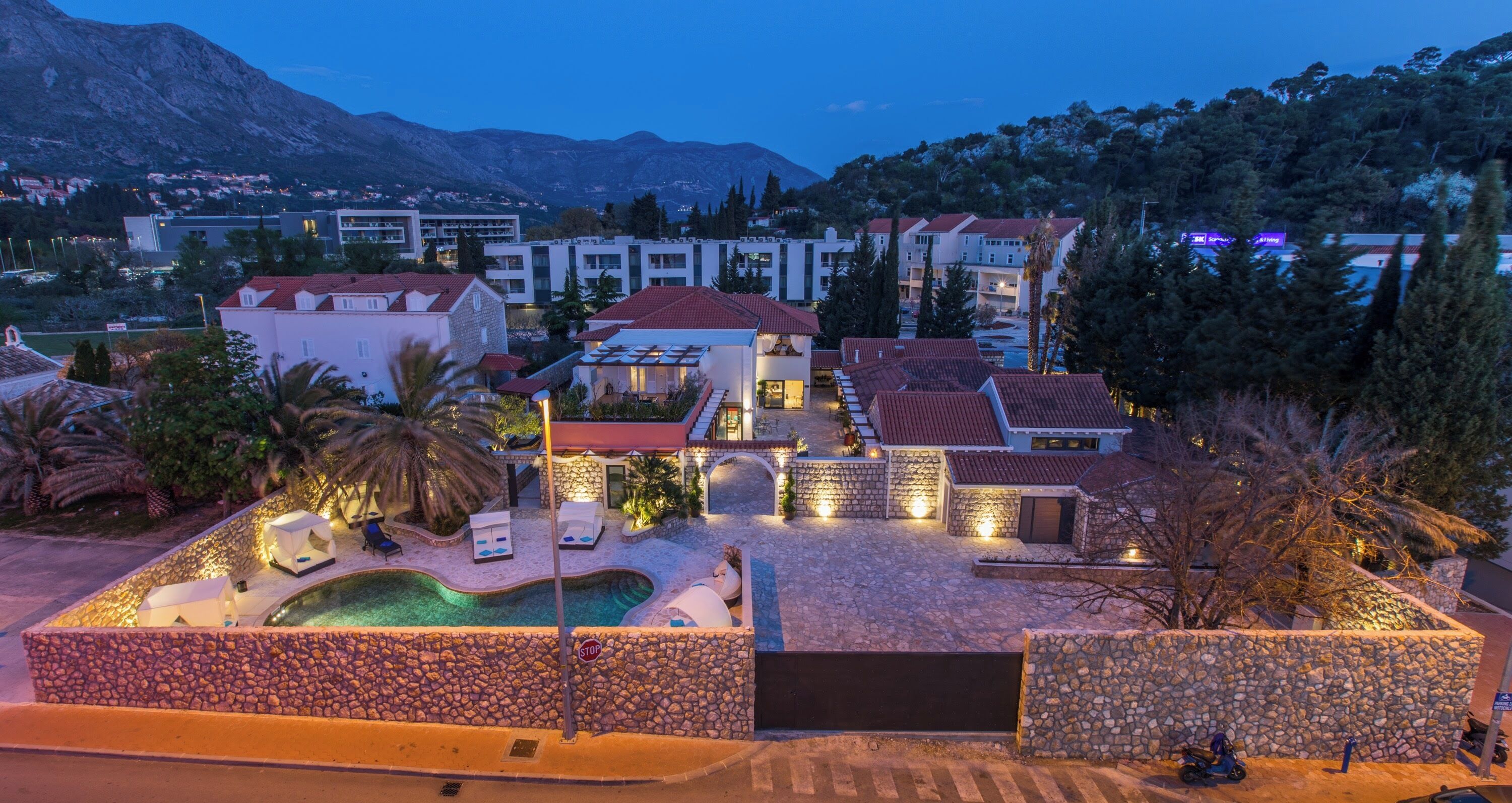 A resort with a swimming pool, multiple buildings, and a mountainous backdrop.