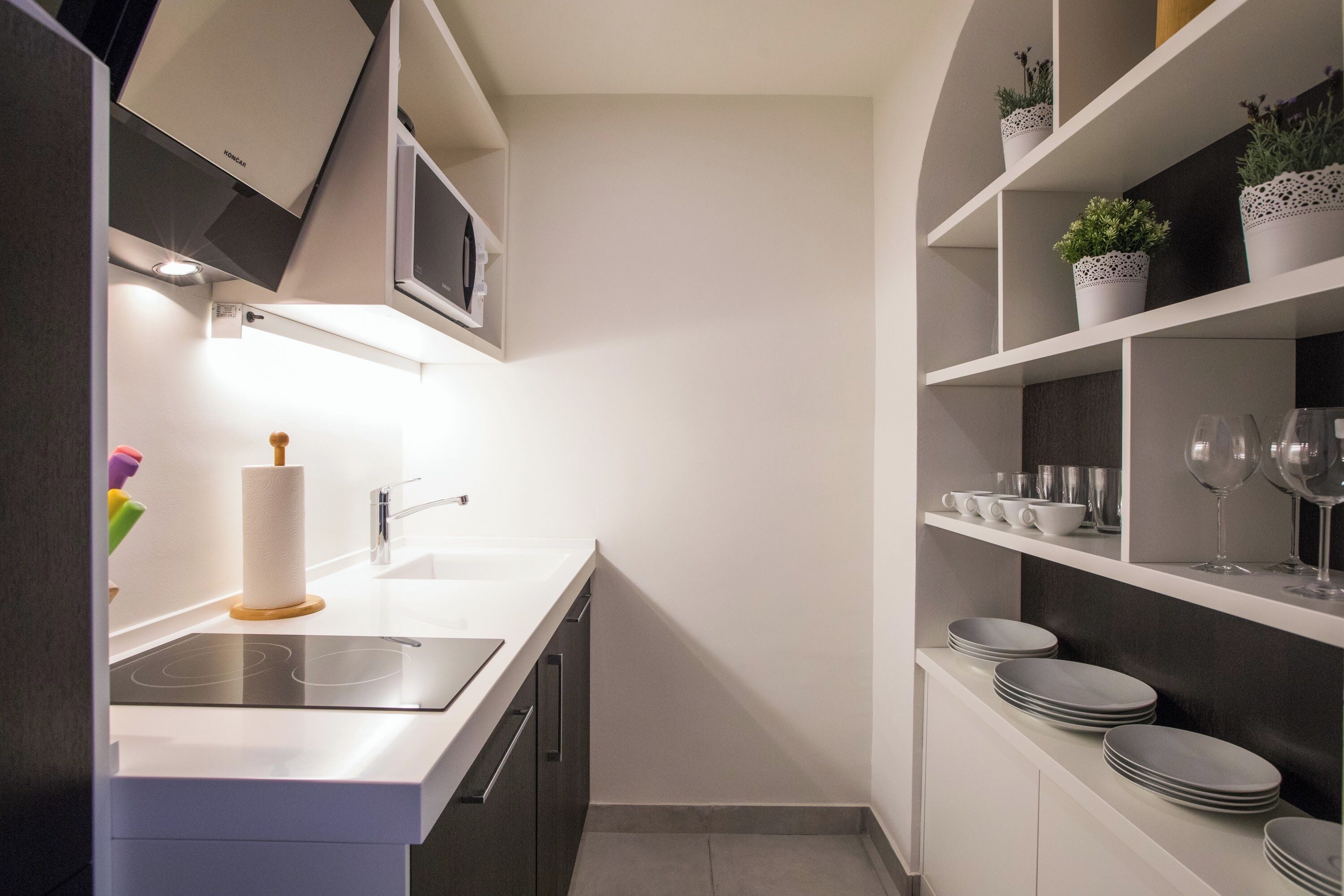 A modern kitchen with a built-in dishwasher, a stainless steel sink, and a white countertop.