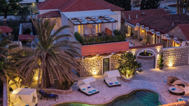 A resort with a swimming pool, lounge chairs, and a palm tree. - Villa Diamond (Zupa dubrovacka)