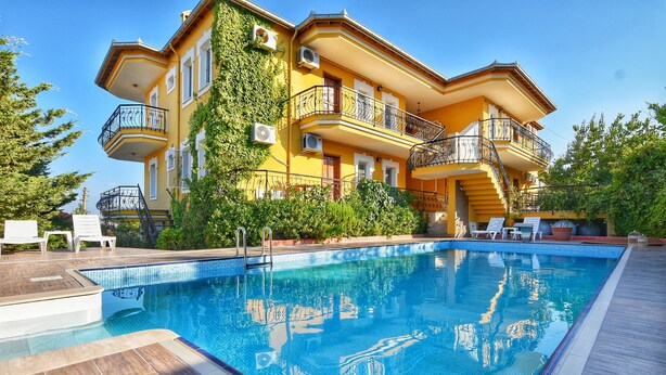 Un gran edificio amarillo con piscina, zona de estar exterior y una escalera que conduce a los pisos superiores.