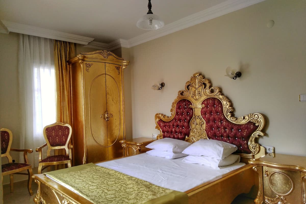 Une chambre avec un grand lit, une armoire et deux chaises.