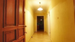 Un pasillo estrecho con puertas de madera y una lámpara en el techo.