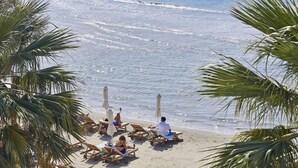Ein Strand mit Liegestühlen und Palmen.