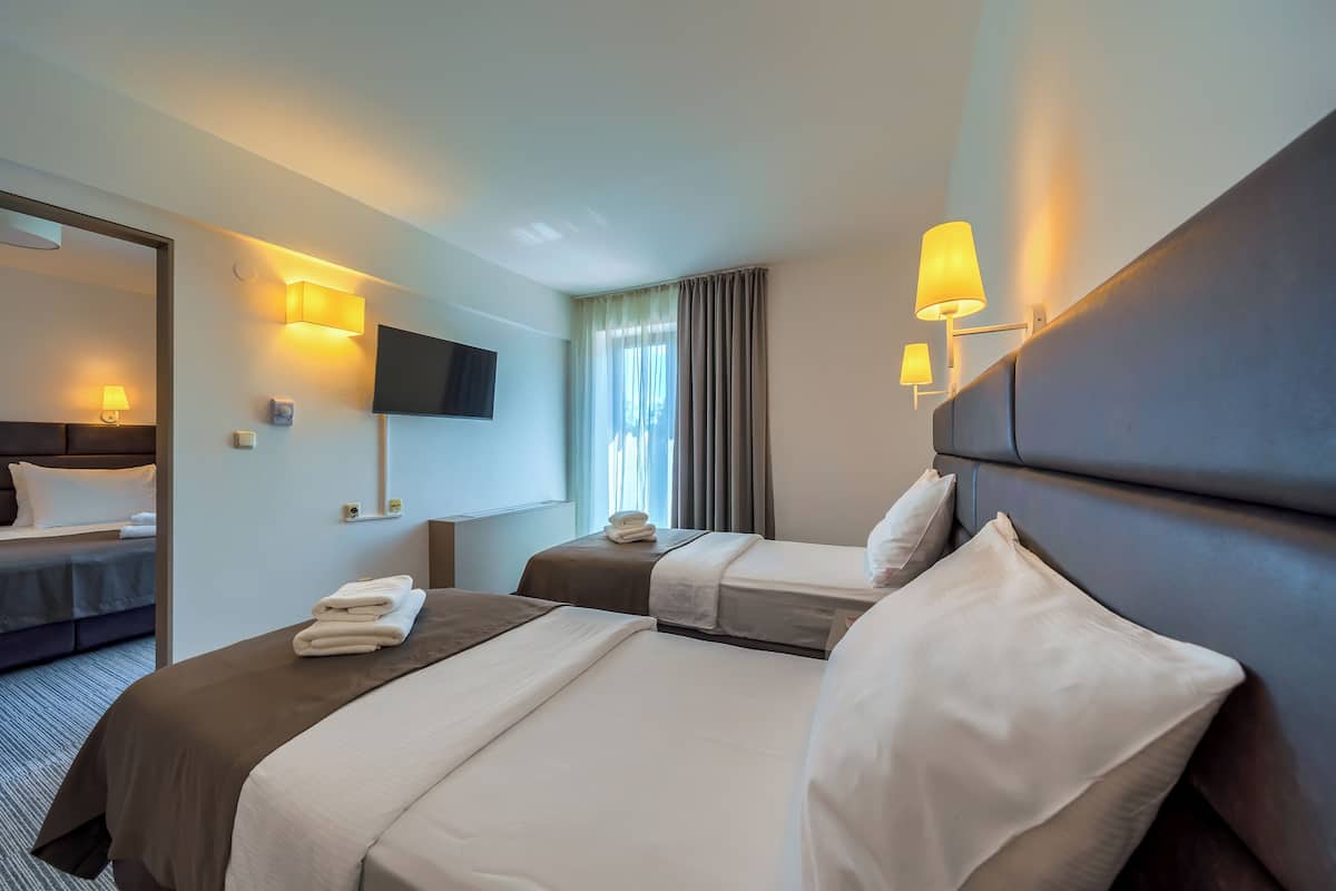 Habitación de hotel con dos camas, televisión y lámparas fijadas a la pared.