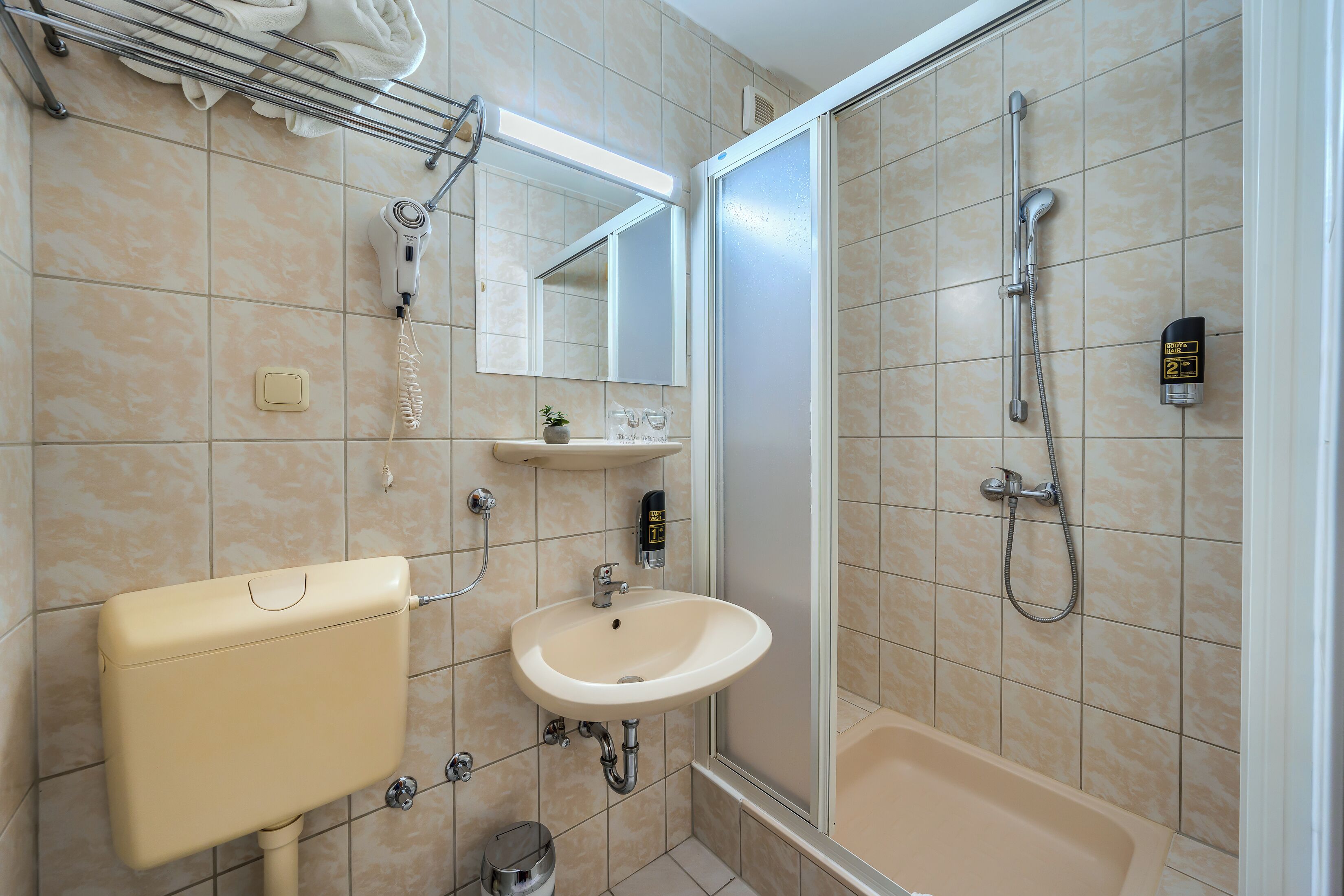 Ein Badezimmer mit Toilette, Waschbecken, Dusche und Spiegel.