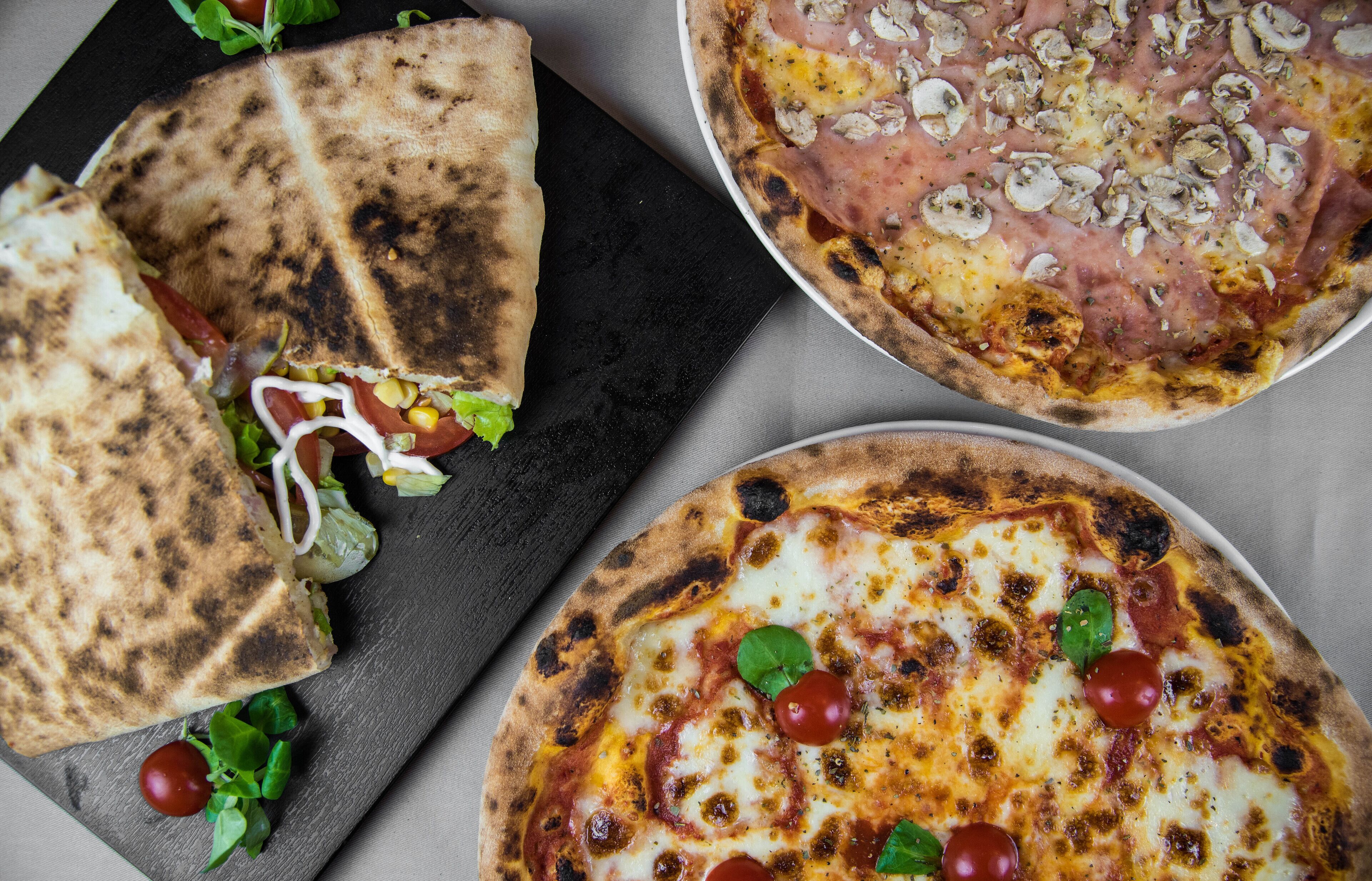 Pizza con jamón y champiñones, una flatbread con lechuga y tomate, y pizza con queso y tomates.
