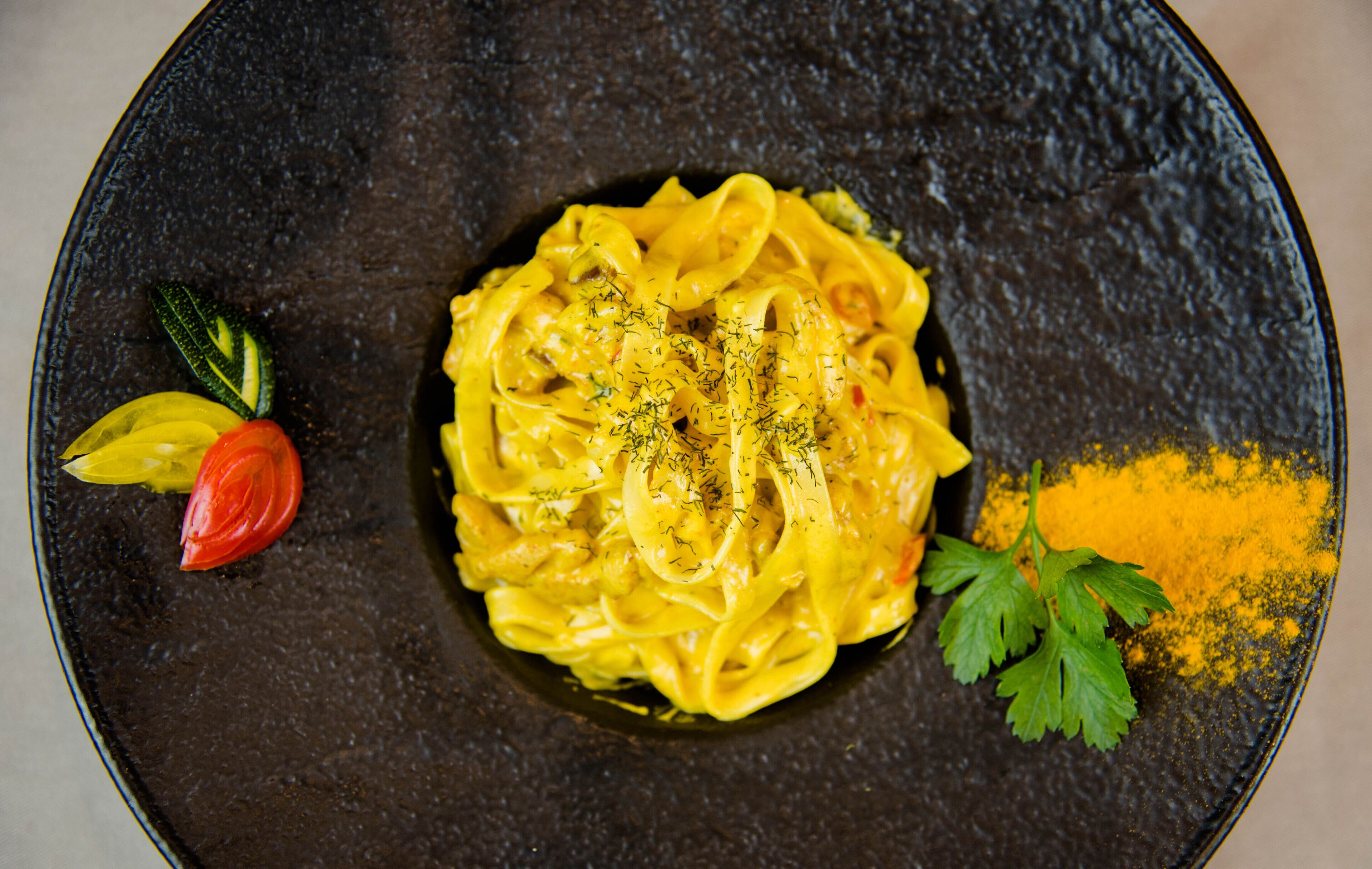 Un plato de pasta con adorno de perejil y un toque de especia amarilla.