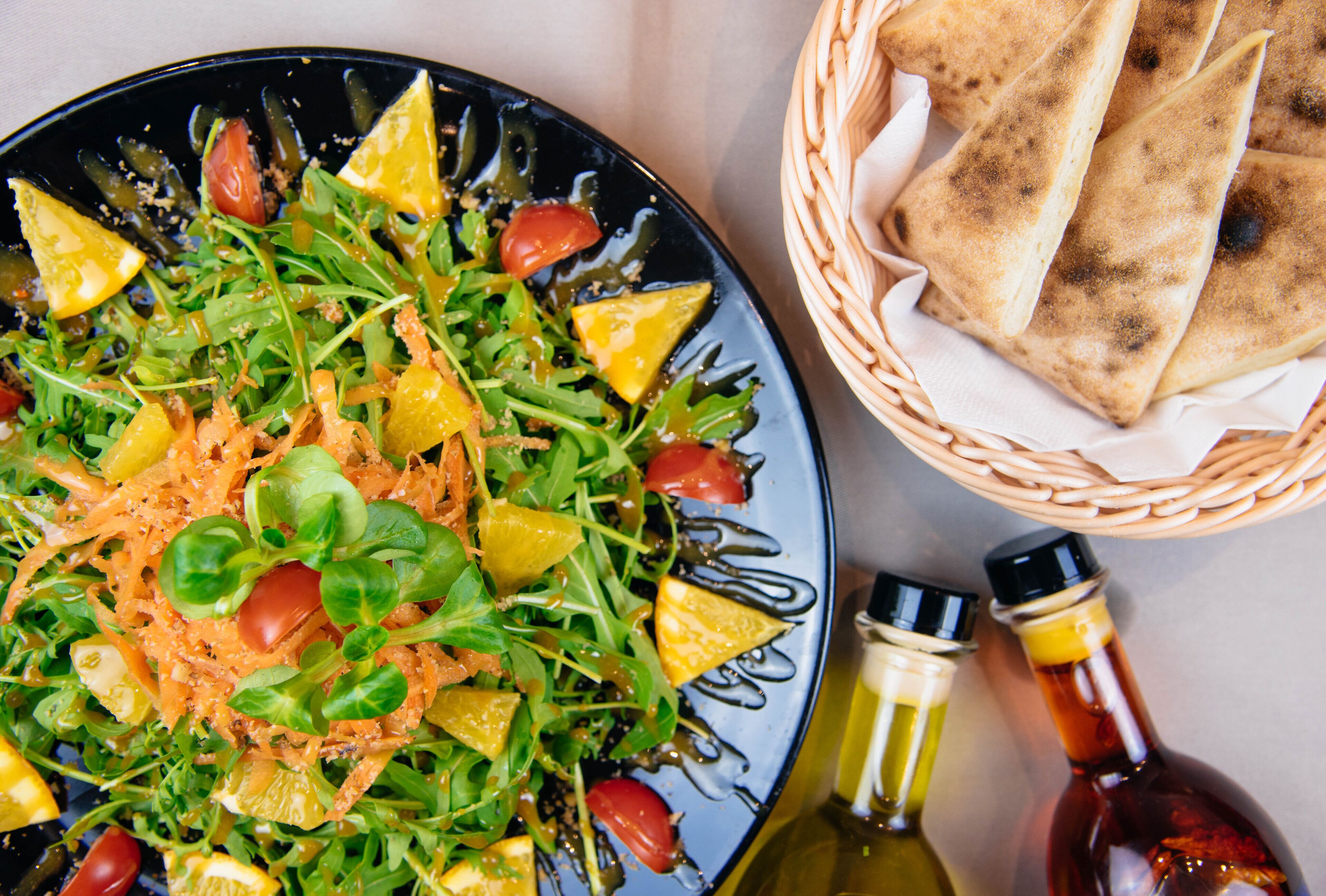 Ein Salat mit verschiedenen Gemüsesorten und ein Korb mit Fladenbrot.