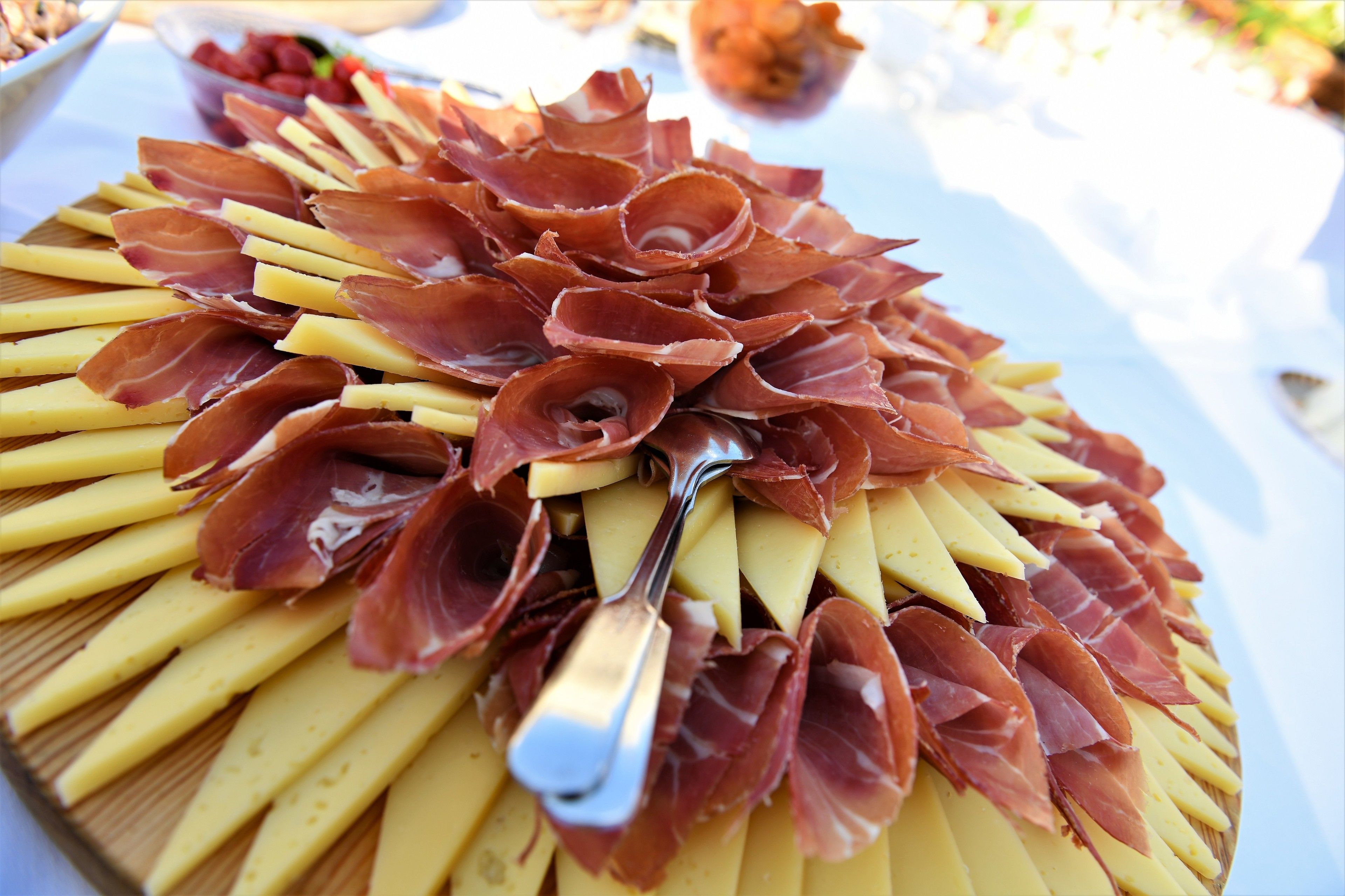 A platter of sliced cheese and cured meats arranged on a wooden board.