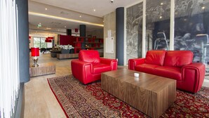 A modern lobby with red leather sofas, a wooden coffee table, and a patterned rug.