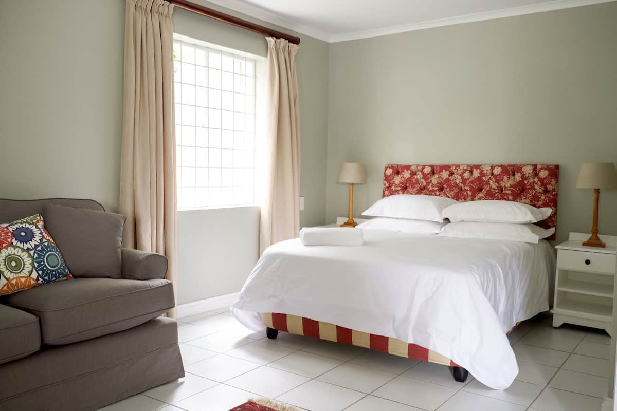 A bedroom with a bed, bedside tables, a sofa, and a window with curtains.