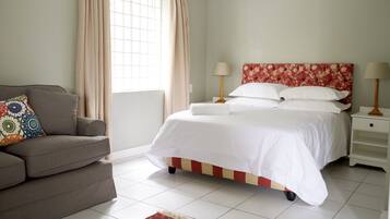 A bedroom with a bed, bedside tables, a sofa, and a window with curtains.