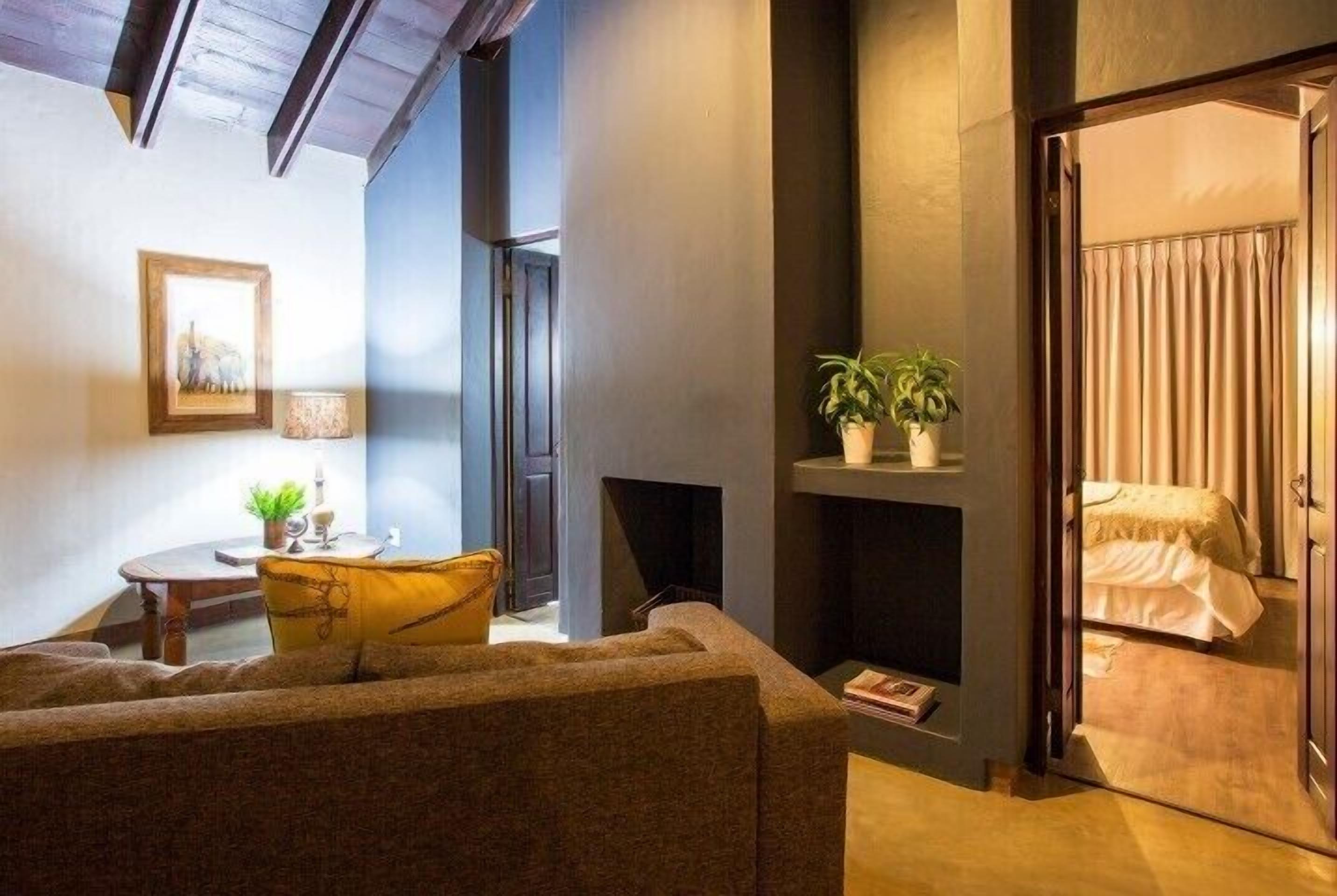 Uma sala de estar aconchegante com um sofá, uma mesinha com uma planta e uma lareira.