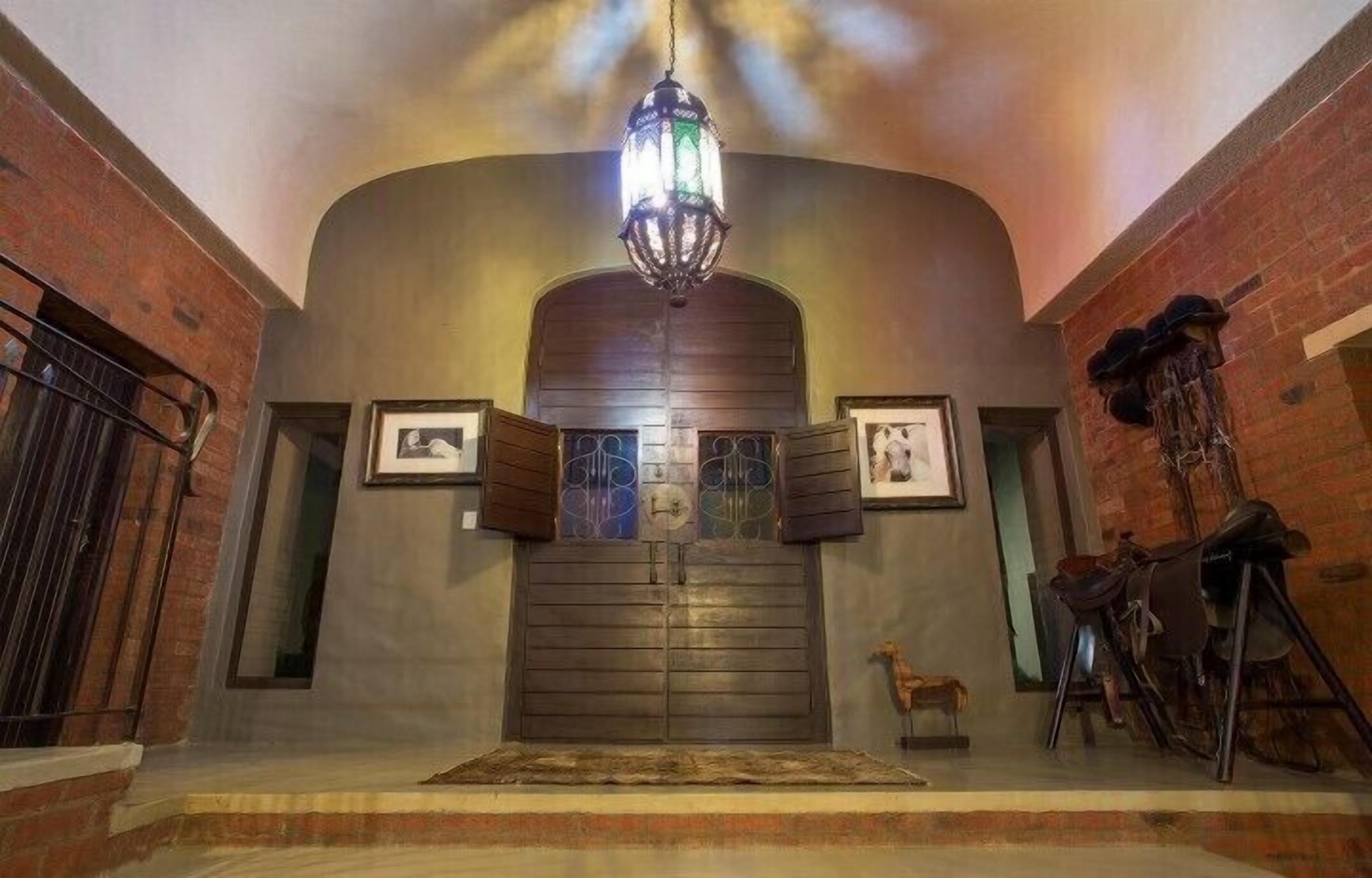 A grand entrance with a large wooden door, a hanging lantern, and a small statue.