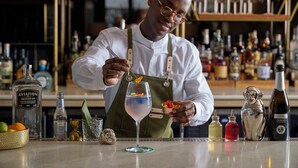 A bartender preparing a cocktail with various ingredients and bottles of liquor on the bar counter. - Viceroy Chicago (Chicago)