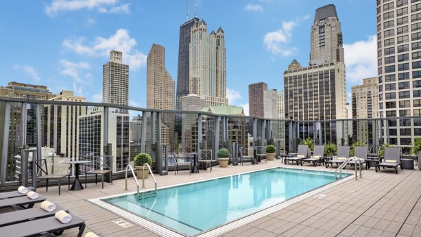 A rooftop pool with lounge chairs and a city skyline in the background. - Viceroy Chicago (Chicago)