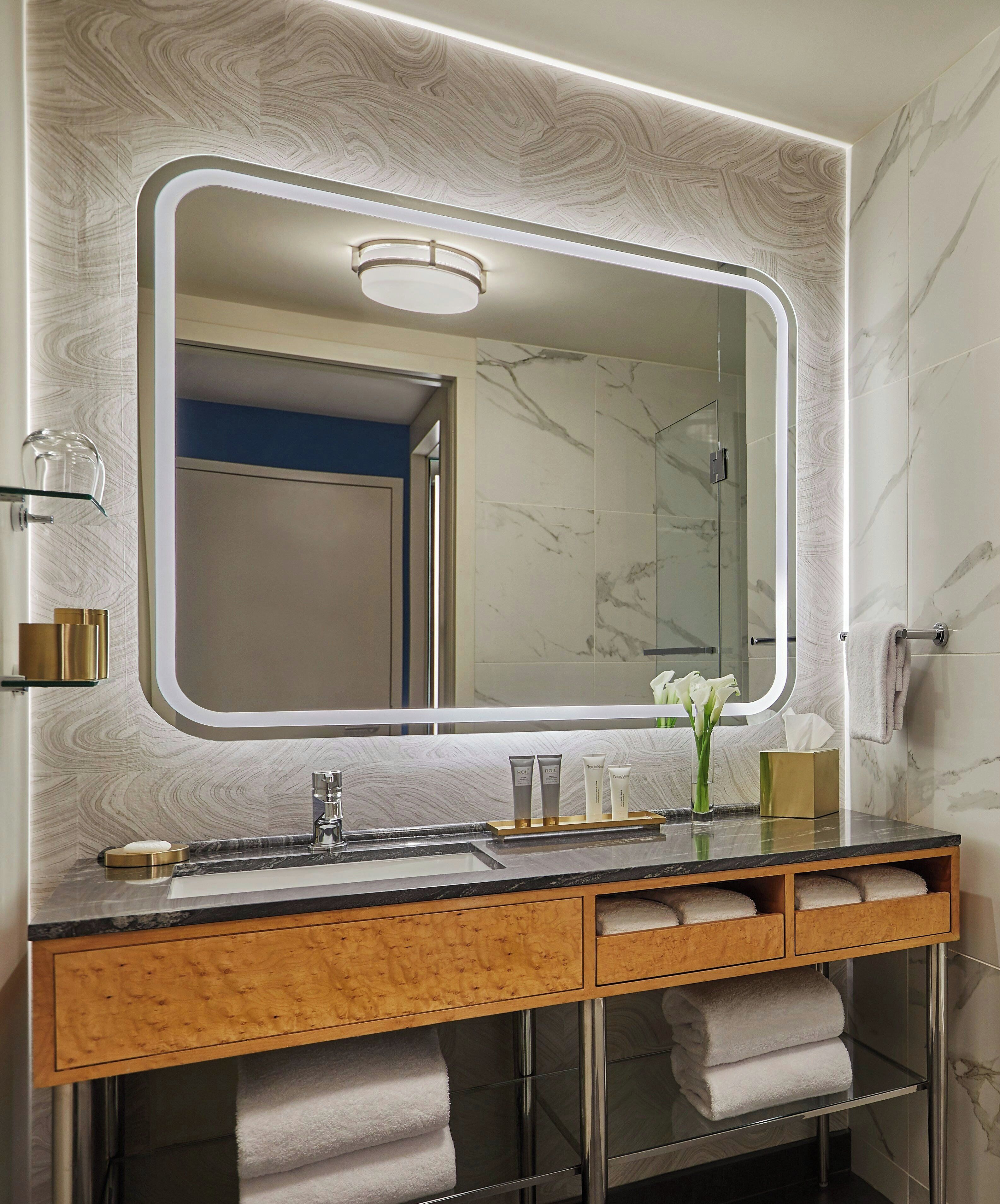 A bathroom with a large mirror, a sink, and a vanity with a wooden cabinet.