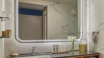 A bathroom with a large mirror, a sink, and a vanity with a wooden cabinet.
