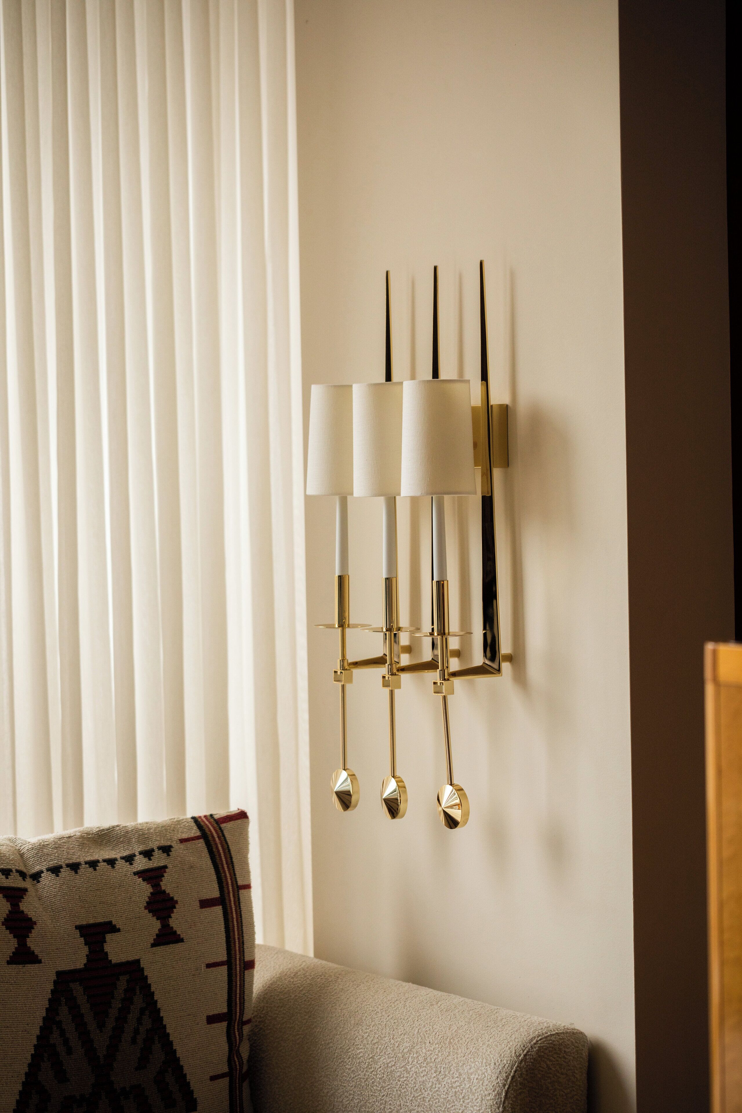 A wall-mounted lamp with three shades and a geometric design.