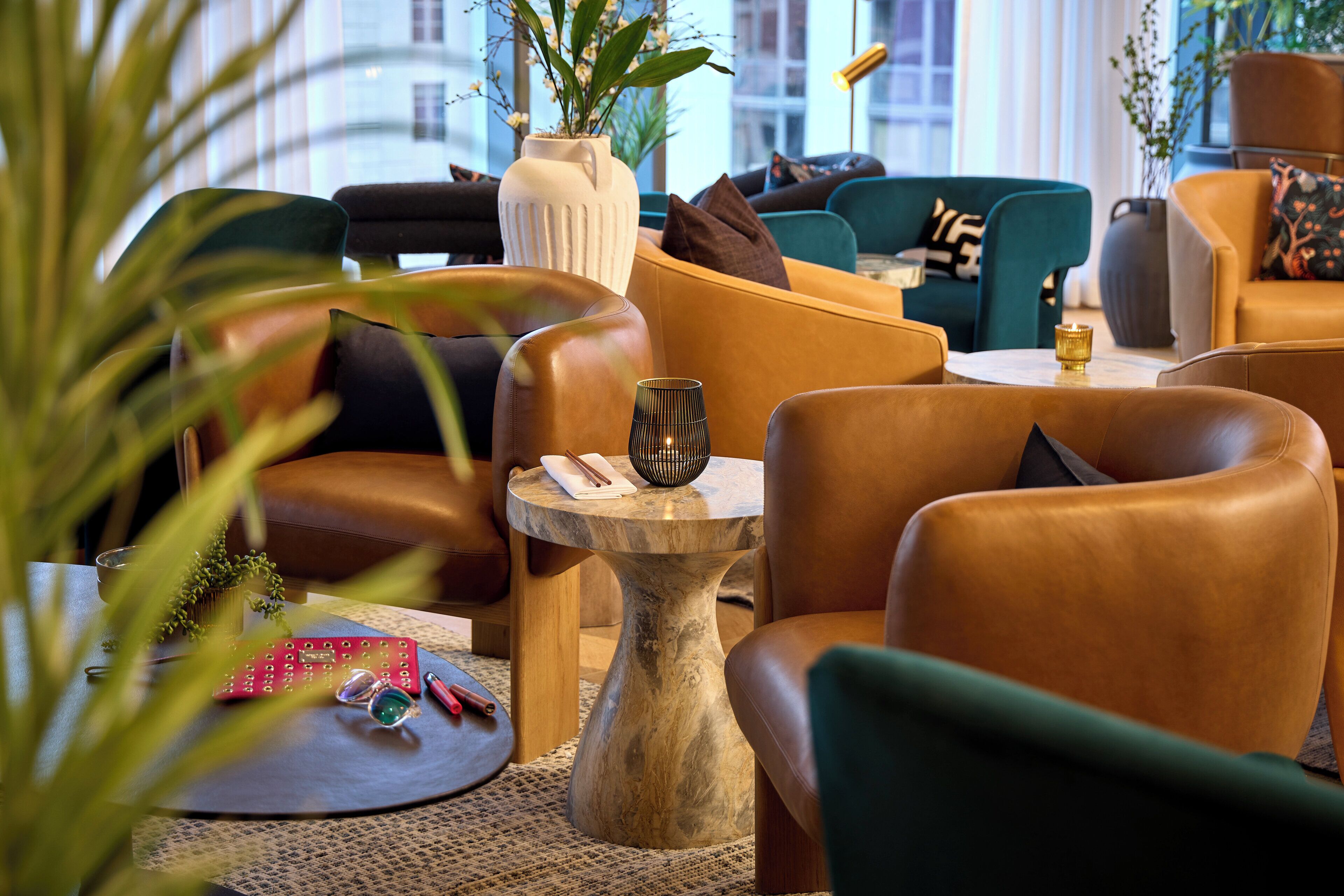 A modern living room with leather sofas, a round coffee table, and decorative plants.