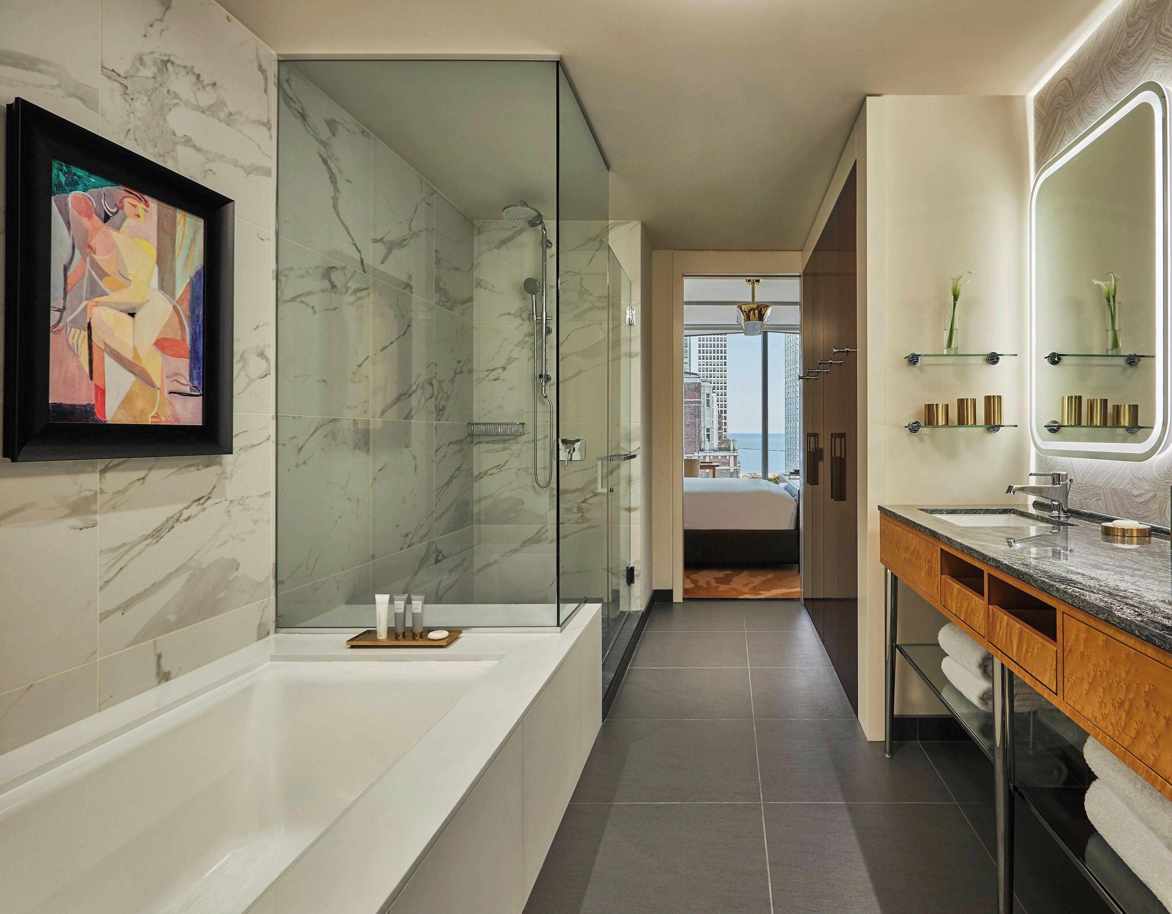 Un bagno moderno con doccia in marmo, uno specchio grande e un quadro appeso al muro.