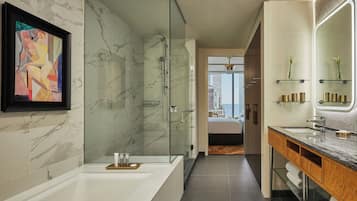 Un bagno moderno con doccia in marmo, uno specchio grande e un quadro appeso al muro.