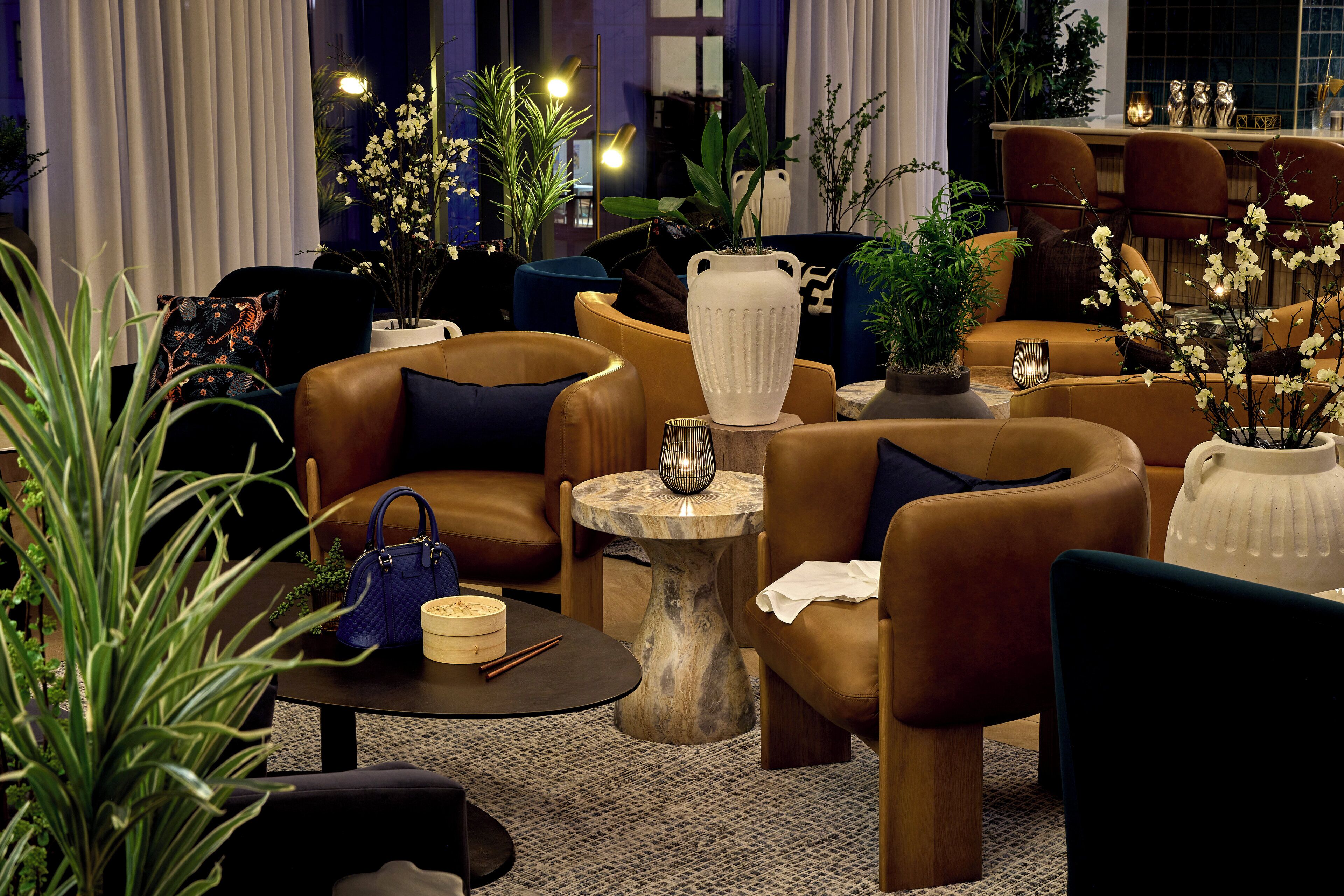 Un salon moderne avec des canapés en cuir, une table basse ronde et des plantes décoratives.