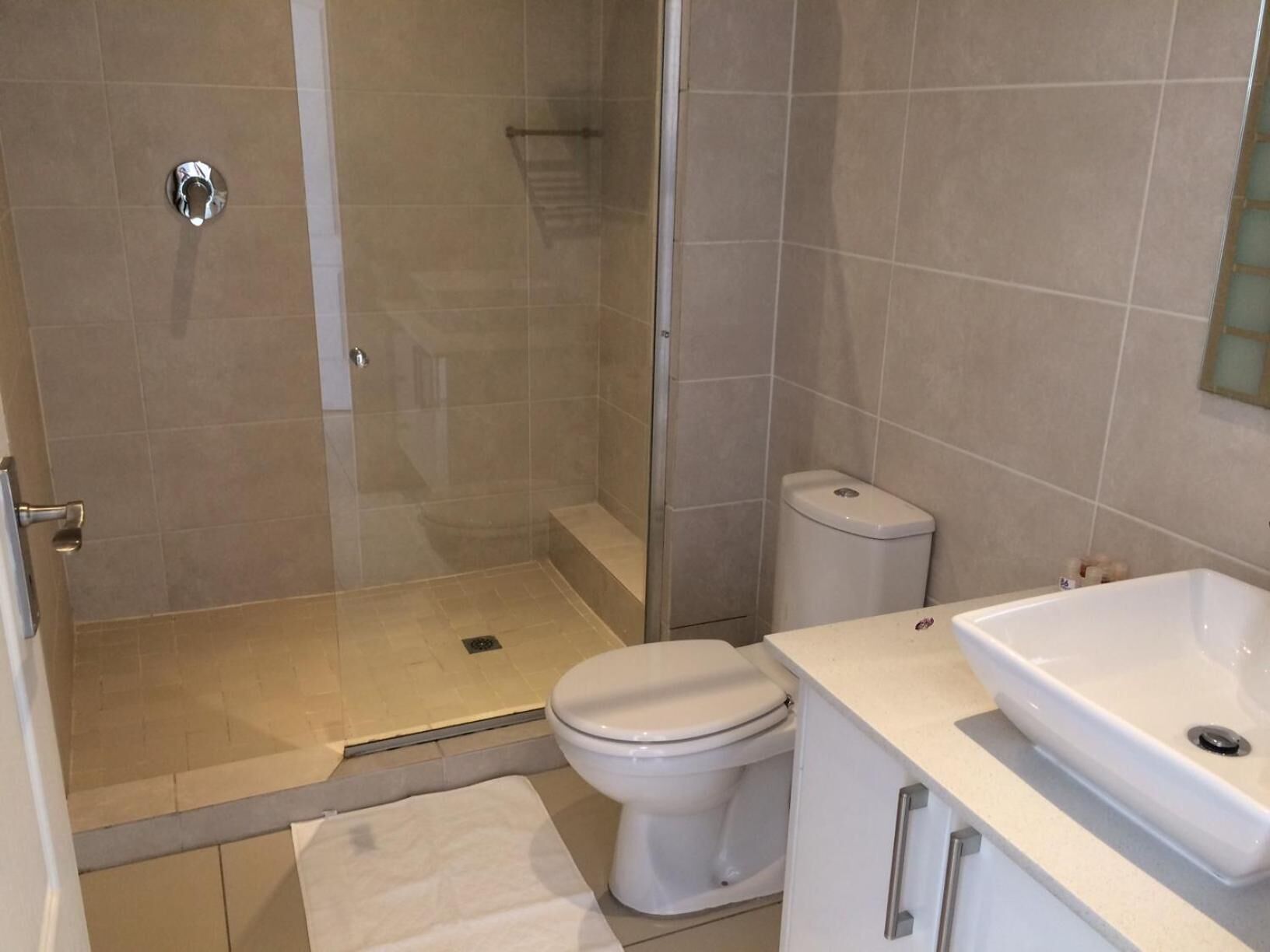 Een badkamer met douche, toilet en wastafel.