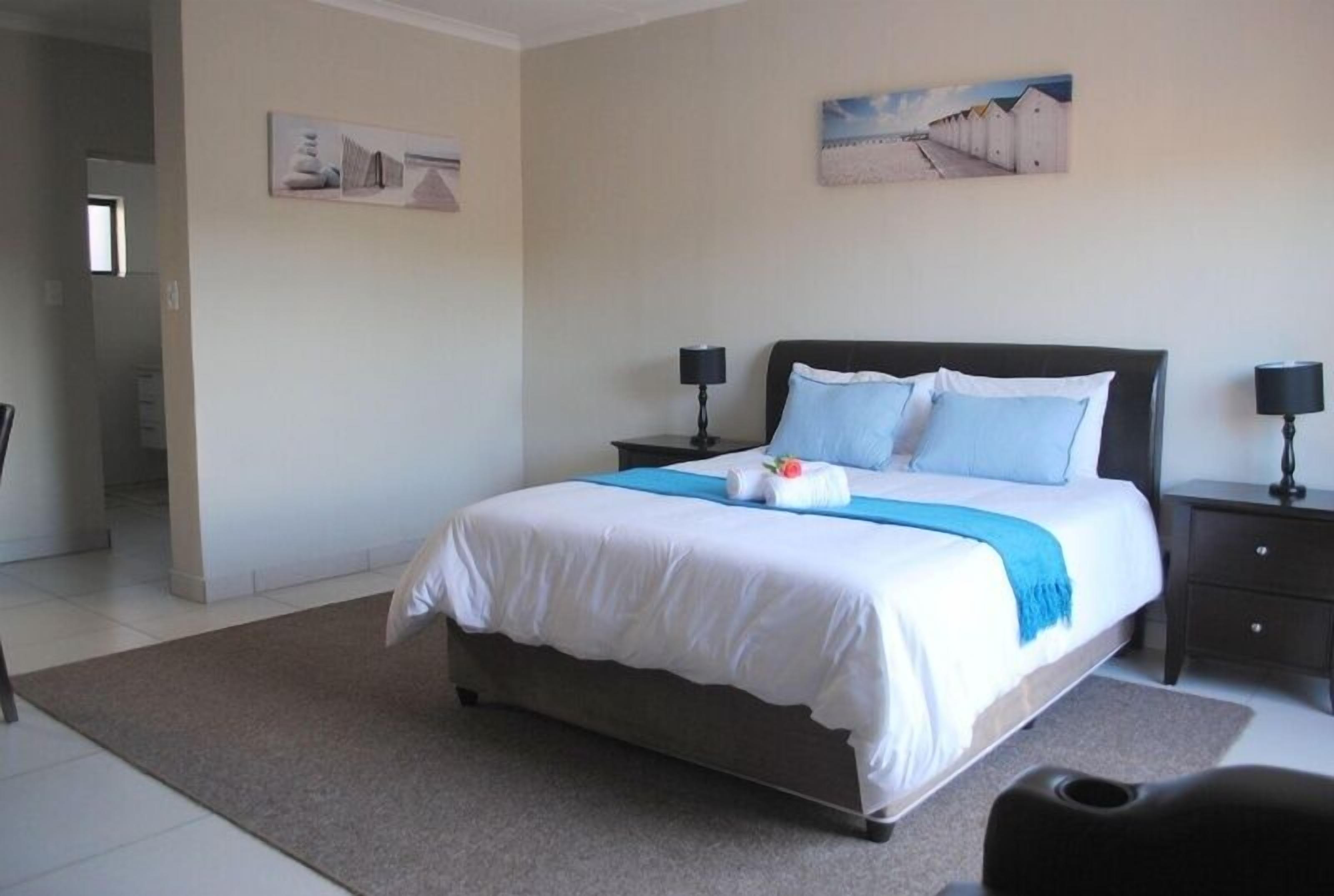 A neatly arranged bedroom with a bed, bedside tables, and artwork on the walls.