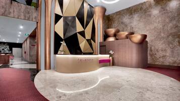 A reception area with a modern design, featuring a geometric wall pattern, a reception desk, and a seating area with a red carpet.
