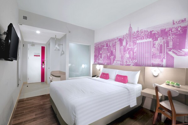 Habitación de hotel con cama, escritorio, silla, televisor y un mural con vista a la ciudad.