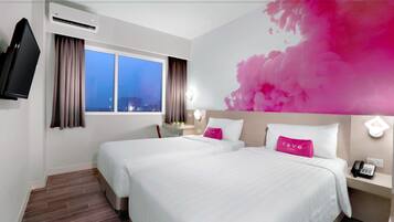 A hotel room with two beds, a TV, a desk with a phone, and a city view through the window.