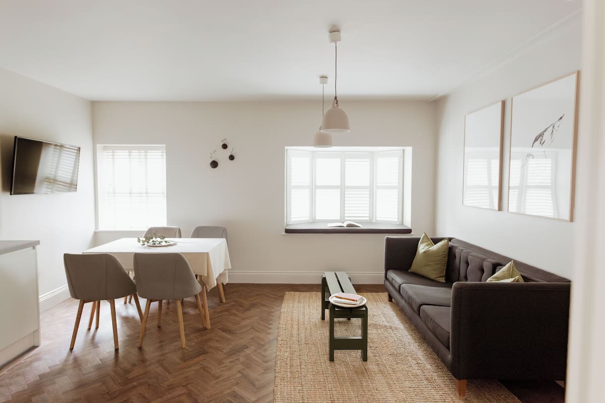 Ein modernes Wohnzimmer mit Essbereich, einer Couch und einem an der Wand befestigten Fernseher.