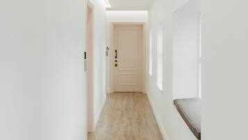 A narrow, well-lit hallway with wooden flooring and white walls.